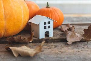 herbstlicher Hintergrund. Spielzeughaus und Kürbis auf Holzhintergrund. Thanksgiving-Banner kopieren Platz. Hygge-Stimmung, Wechsel der Jahreszeiten. hallo herbst mit familien-halloween-party. foto