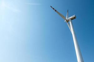 rotierende Blätter eines Windmühlenpropellers auf blauem Himmelshintergrund. Windkrafterzeugung. reine grüne Energie. foto