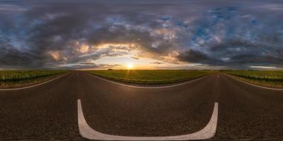 volles sphärisches nahtloses hdri-panorama 360-grad-winkelansicht auf asphaltstraße zwischen feldern im sommerabendsonnenuntergang mit fantastischen wolken in equirectangularer projektion, für vr-ar-virtual-reality-inhalte foto