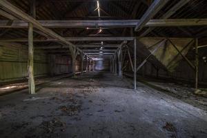 im dunklen, verlassenen, ruinierten, verfallenden Hangar aus Holz mit verrottenden Säulen foto