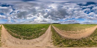 Vollständiges, nahtloses sphärisches HDRI-Panorama 360-Grad-Winkelansicht auf einer unbefahrenen Schotterstraße zwischen Feldern am Frühlingstag mit bewölktem Himmel in gleichrechteckiger Projektion, bereit für VR- und Virtual-Reality-Inhalte foto