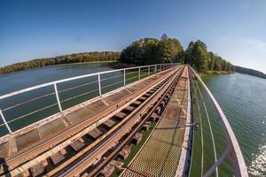 Eisenstahlrahmenkonstruktion einer Schmalspurbahnbrücke über den Fluss. Weitwinkelansicht foto