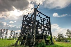 Reste der alten verbrannten Windmühle auf dem Feld vor dem Regen foto