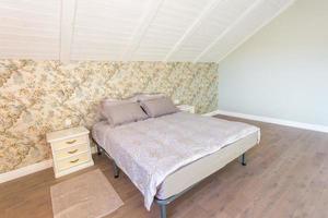 Doppelbett mit Kissen im Inneren des modernen Schlafzimmers in einer Dachgeschosswohnung im hellen Farbstil teurer Wohnungen foto