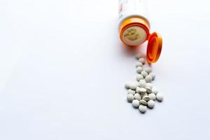 Pillen kommen aus der Medizinflasche, auf weißem Hintergrund