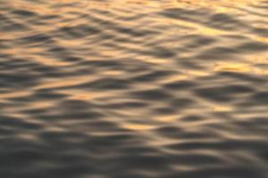 sonnenuntergangswasser reflektiert kräuselungen bei sonnenlicht. abstrakte goldene reflexion über wasser sonnenuntergang foto