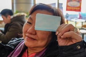 Alte asiatische Frauen lassen eine Süße sein Zugticket zeigen, verspotten foto