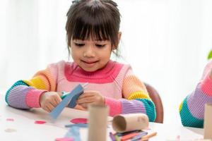 porträt eines kleinen asiatischen mädchens, das ein papier in aktivitäten im diy-unterricht in der schule schneidet. schere schneidet papier. foto