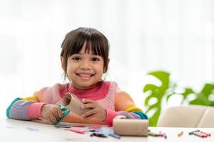 porträt eines kleinen asiatischen mädchens, das ein papier in aktivitäten im diy-unterricht in der schule schneidet. schere schneidet papier. foto