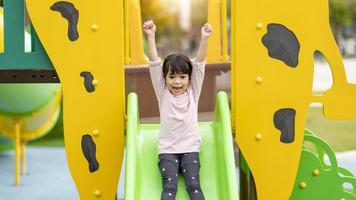 Kind spielt auf Spielplatz im Freien. kinder spielen auf dem hof der schule oder des kindergartens. aktives kind auf bunter rutsche und schaukel. gesunde sommeraktivität für kinder. kleiner Junge, der draußen klettert. foto