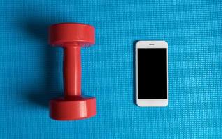 Blaue Yogamatte, Hantel mit Smartphone foto