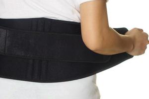 Frau trägt Rückenstützgürtel isoliert auf weiß foto