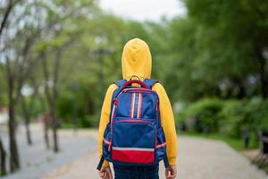 Ein Junge in einem gelben Sweatshirt mit einem Rucksack auf dem Rücken, der zur Schule geht. zurück zum schulkonzept foto