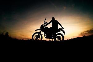 Herren-Silhouetten und Touren-Motocross-Bikes. Park zum Entspannen in den Bergen am Abend. abenteuerreise- und freizeitkonzept foto