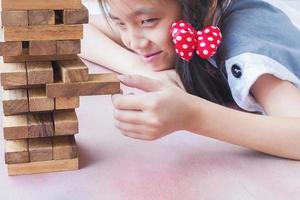 asiatisches kind spielt holzblockturmspiel zum üben von körperlichen und geistigen fähigkeiten foto