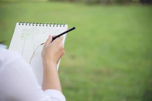 Entspannen Sie Frau, die Aquarellkunstwerk in der grünen Gartenwaldnatur malt - Menschen mit kreativer Kunst in der Natur Stressabbau und Meditationskonzept foto