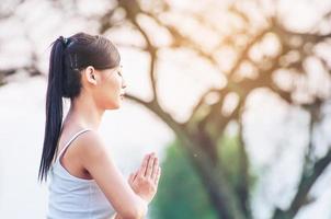 junge Dame, die Yoga-Übungen im Außenbereich der grünen Wiese macht und Ruhe und Frieden im Meditationsgeist zeigt - Menschen praktizieren Yoga für Meditations- und Übungskonzept foto