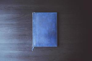 Draufsicht auf das alte blaue Buch auf dem schwarzen Schreibtisch. foto