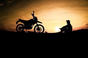 Herren-Silhouetten und Touren-Motocross-Bikes. Park zum Entspannen in den Bergen am Abend. abenteuerreise- und freizeitkonzept foto