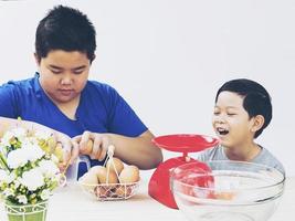 Kinder bereiten fröhlich Eier für die Herstellung eines Kuchens zu foto