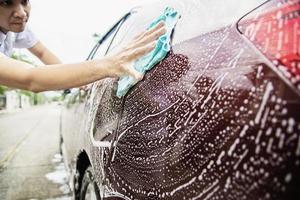 mann wäscht auto mit shampoo - alltagsautopflegekonzept foto