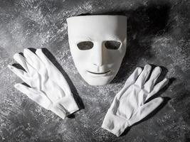weiße Maske mit Handschuh auf grauem Grunge-Hintergrund. foto