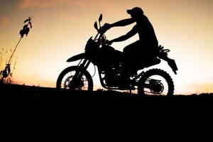 Herren-Silhouetten und Touren-Motocross-Bikes. Park zum Entspannen in den Bergen am Abend. abenteuerreise- und freizeitkonzept foto