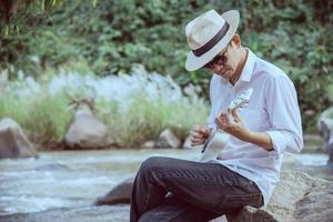 mann spielt ukulele neu im lebensstil der flussmenschen und musikinstrumente im naturkonzept foto