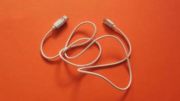 Weißes Spannungsladegerät mit USB-Kabel für Telefon- und Geräteladung auf farbigem und leuchtendem Hintergrund foto
