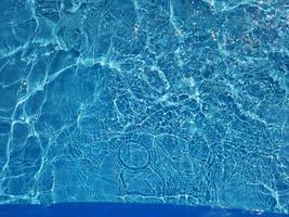Unschärfe verschwommenes blaues Wasser, das im Meer scheint. geplätscherter wasserdetailhintergrund. die wasseroberfläche im meer, ozeanhintergrund. Wasserwelle unter Meerestextur Hintergrund. foto