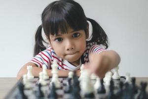 asiatisches kleines mädchen, das zu hause schach spielt. ein schachspiel foto