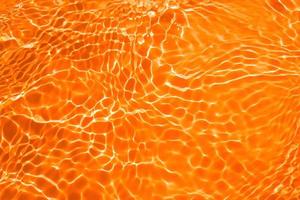 Unscharfe, transparente, orangefarbene, klare, ruhige Wasseroberflächenstruktur mit Spritzern und Blasen. trendiger abstrakter naturhintergrund. wasserwelle im sonnenlicht mit kopierraum. blaue aquarellbeschaffenheit foto
