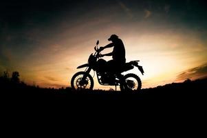 Herren-Silhouetten und Touren-Motocross-Bikes. Park zum Entspannen in den Bergen am Abend. abenteuerreise- und freizeitkonzept foto