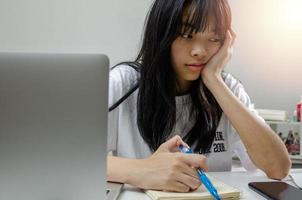 Mädchen mit Stift schreiben Buch lernen digitales Internet-Video online Computer-Laptop zu Hause. foto