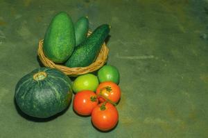 Kombination aus Obst und Gemüse Avocado Kürbis grüne Zitrone und Tomate auf Holztisch hautnah. foto