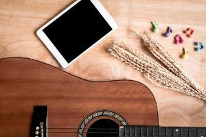 Draufsicht der akustischen Gitarre mit Tablet-Touch-Computer-Gadget auf Holztischhintergrund. foto