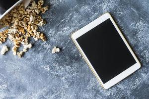 weiße Tablet-Touch-Computer-Gadget mit Popcorn auf Grunge-Hintergrund. foto