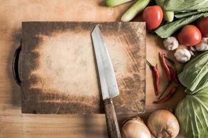 Draufsicht auf Messer auf Holzhackklotz mit frischem Gemüse. foto