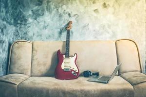 e-gitarre mit laptop und kopfhörer auf einem sofa. Vintage-Ton. foto