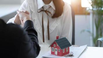Käufer und Immobilienmakler haben zugestimmt, Händchen haltend zu kaufen und zu verkaufen, um ein Haus zu mieten oder zu kaufen, nachdem die Dokumente im Büro unterzeichnet wurden. foto
