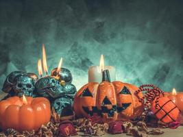 Halloween-Kürbisse mit Kerzenlicht und Totenköpfen auf dunklem Hintergrund. Vintage-Ton