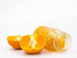 frische Orange mit Orangenmarmelade im Glas auf weißem Hintergrund. foto