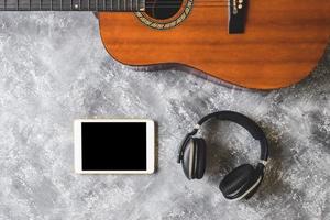 Draufsicht der Gitarre mit Kopfhörer und Tablet auf Grunge-Hintergrund foto