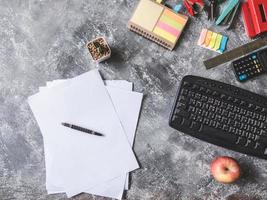 Blick von oben auf das Blatt Papier mit Büromaterial auf grauem Hintergrund foto