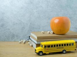 das schulbusspielzeug und der apfel auf dem holztisch für den schulanfang oder das bildungskonzept foto