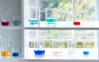 Vorbereiten von Laborgeräten wie Glaswaren, Röhrchen mit Blau und Flüssigkeit auf dem weißen Tisch. Das Chemieexperiment in der wissenschaftlichen Forschung