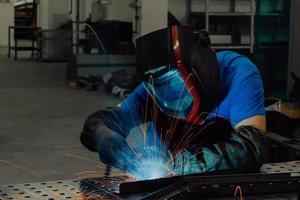 professioneller Schweißer aus der Schwerindustrie, der in der Fabrik arbeitet, einen Helm trägt und mit dem Schweißen beginnt. selektiver Fokus foto