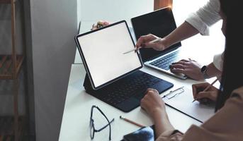 zwei geschäftsfrauen treffen sich in einem besprechungsraum zu einer geschäftsberatung mit einem laptop und einem tablet. modell eines laptops mit einem leeren bildschirm foto