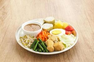 gado gado, indonesischer traditioneller gemüsesalat mit erdnusssoße, reiskuchen, tofu und ei foto