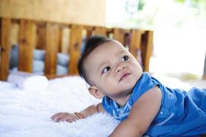 Ein wunderschönes 6 Monate altes Baby mit großen Augen liegt auf dem Bett. foto